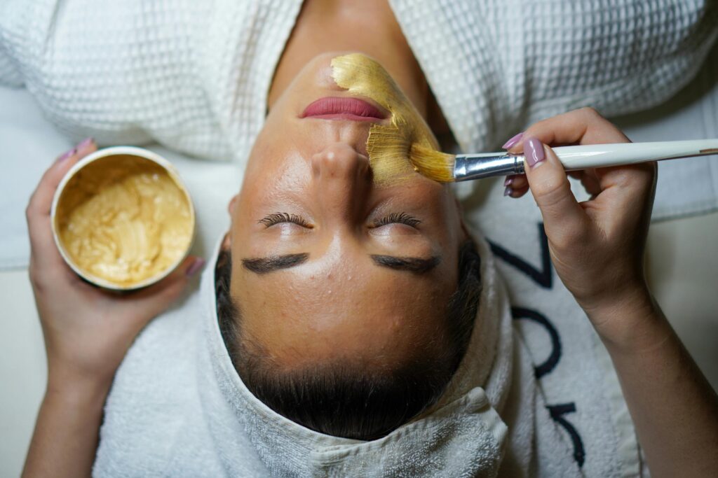 A woman enjoying a gold facial mask for relaxation and skincare at a spa.